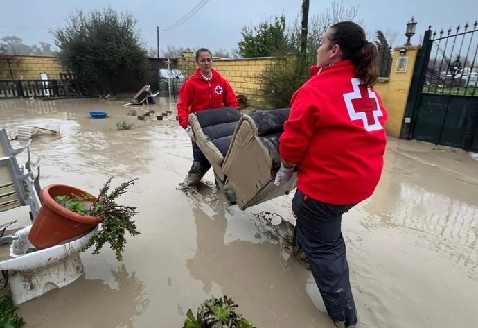 Dos  voluntarias de Cruz Roja retiran enseres de viviendas inundadas por las borrascas en Córdoba.