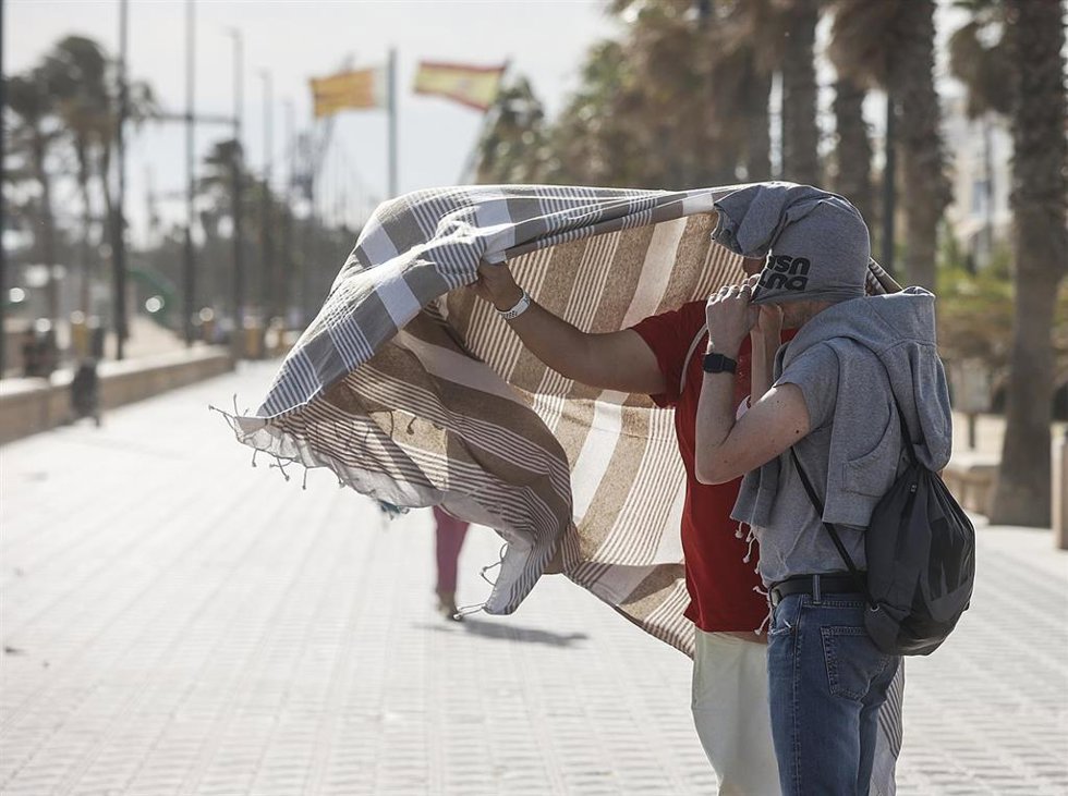 Archivo - Dos personas se refugian del viento