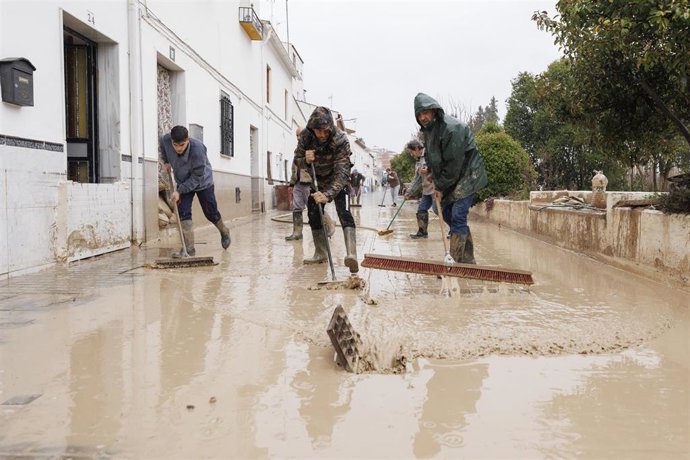 Vecinos de Villanueva Mesía (Granada) se afanan en sacar el agua y barro de sus casas tras la crecida del Río Genil por el paso de la borrasca 'Leonardo'.