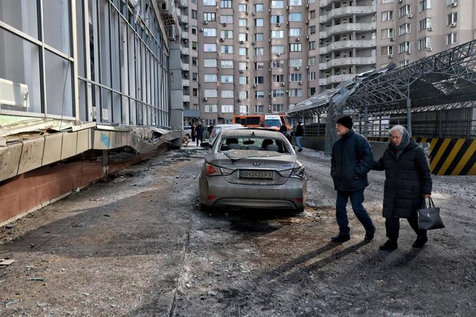 Una pareja de ancianos cruza una calle cubierta de cristales rotos y escombros tras un ataque nocturno con drones rusos en Odesa, Ucrania
