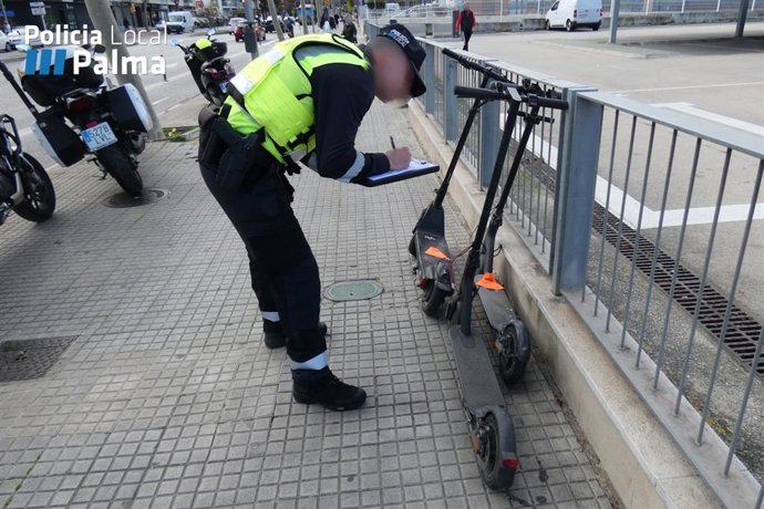 Un agente de la Policía Local de Palma inspecciona un patinete eléctrico en la vía pública.