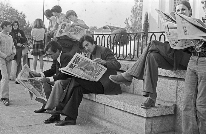 Simpatizantes y curiosos leyendo los periódicos en las inmediaciones del Palacio de El Pardo para conocer las novedades en la evolución del estado de salud de Franco