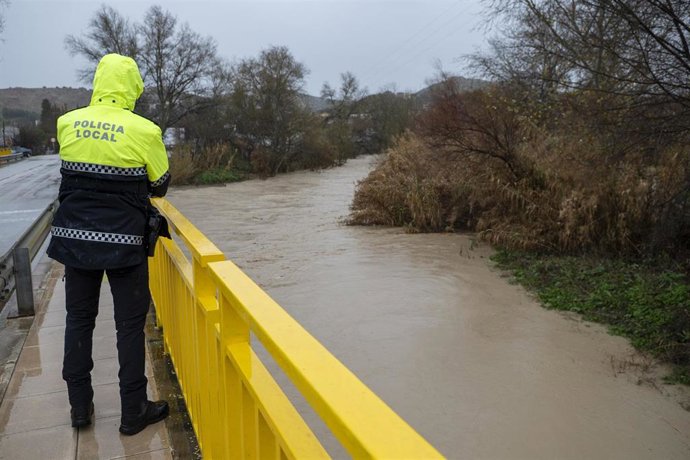 Imagen de archivo de un policía Local vigilando la crecida del río Guadalbullón a su paso por Puente Tablas.