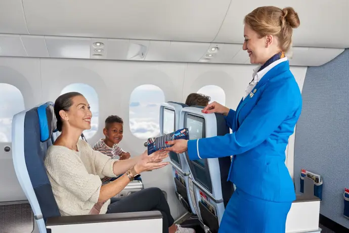 Una azafata atiende a una pasajera y su hijo - KLM - Archivo