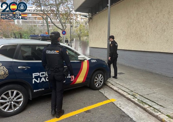 Dos agentes frente a un coche de la Policía Nacional en Palma. 