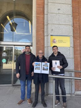 El alcalde de La Guardia de Jaén, Juan Morillo (c), acompañado por dos concejales, muestra el proyecto para concluir la restauración del castillo.