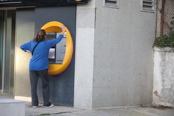 Archivo - Una mujer saca dinero en un cajero automático, a 15 de octubre de 2025, en Cerceda, Madrid (España). 