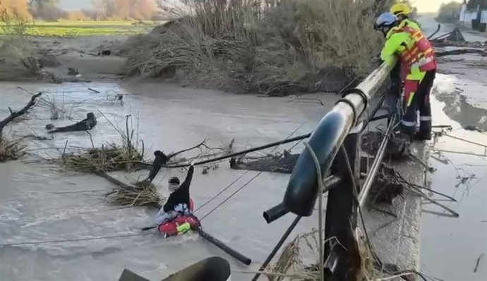 Rescate de los bomberos a la persona atrapada en el turismo caído al río.