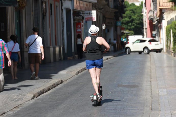 Archivo - Imagen de archivo de una persona circulando en un patinete eléctrico en una calle del centro de Sevilla.