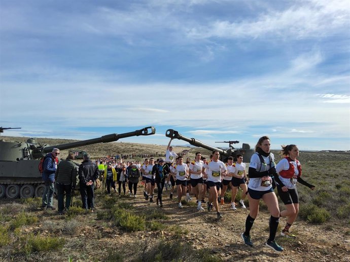 Paseo de corredores y andarines bajo los cañones de dos blindados en el recorrido de la XVIII Carrera del Ebro.