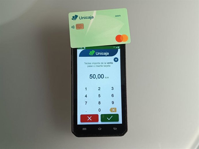 Archivo - TPV y una tarjeta bancaria.