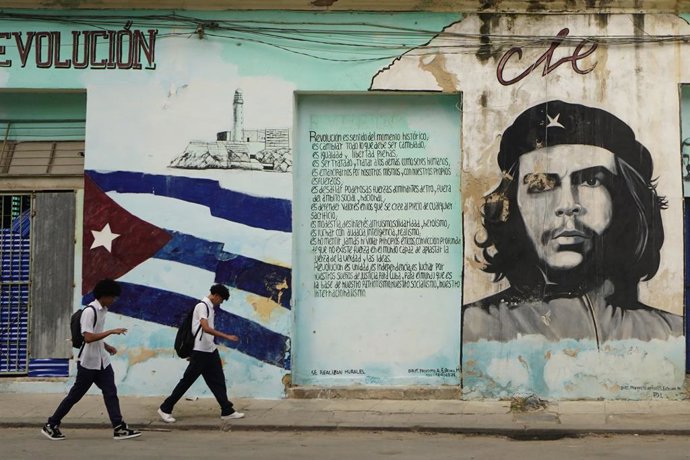 HAVANA, 26 de janeiro de 2026 — Dois jovens passam por uma parede pintada com o retrato de Che Guevara, em Havana, Cuba, em 26 de janeiro de 2026.