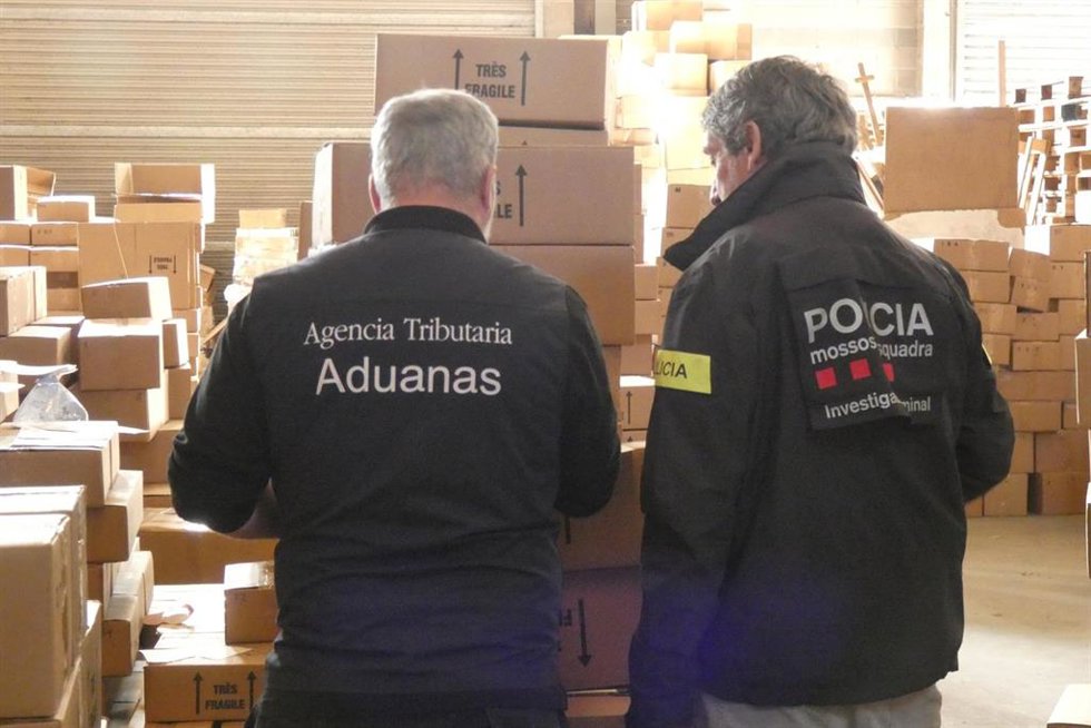 Agentes de los Mossos d'Esquadra y del Servicio de Vigilancia Aduanera con el material intervenido