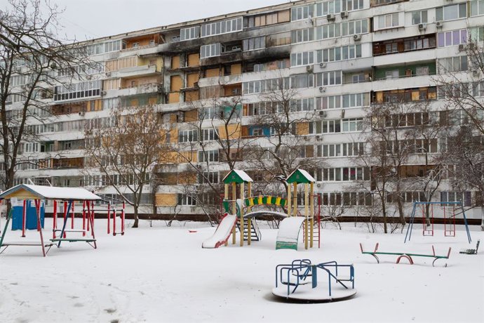 16 de fevereiro de 2026, Kiev, Ucrânia: Painéis de aglomerado vedam as janelas do prédio residencial danificado pelo ataque com mísseis e drones russos em 25 de novembro de 2025, enquanto a neve cobre o playground no inverno, Kiev, Ucrânia, 16 de fevereir