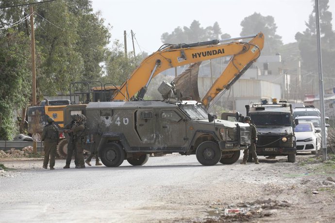 NABLUS, Feb. 16, 2026  -- Members of Israeli forces stand guard as an Israeli excavator demolishes a car repair shop in south of Nablus in the West Bank, Feb. 16, 2026.