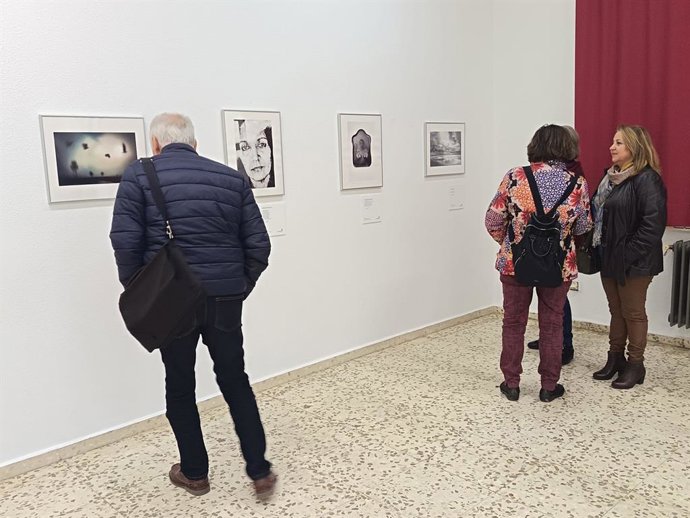 Varias personas observan obras de la exposición 'Foto Poética Hernandiana IV'.