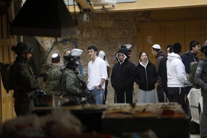 Soldados israelíes y un grupo de colonos judíos en la ciudad de Hebrón, en Cisjordania