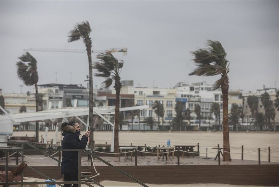 Archivo - Dos personas caminan en la Playa de la Malvarrosa con viento en imagen de archivo