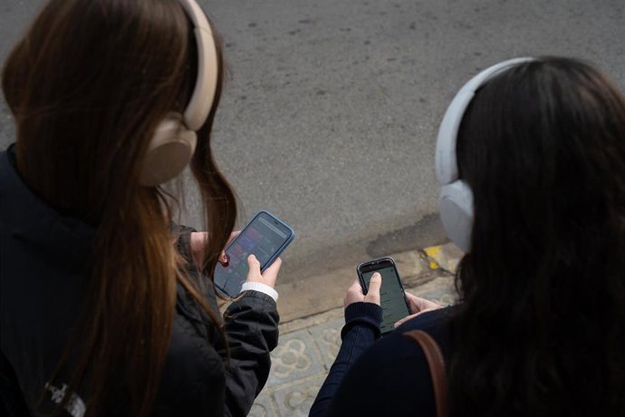 Archivo - Dos personas usan el teléfono móvil, a 1 de febrero de 2024, en Barcelona, Catalunya (España).