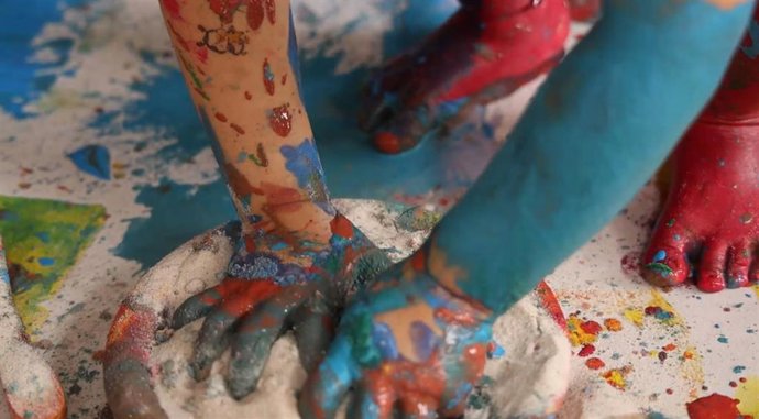 Un niño juega con pintura en una escuela infantil.