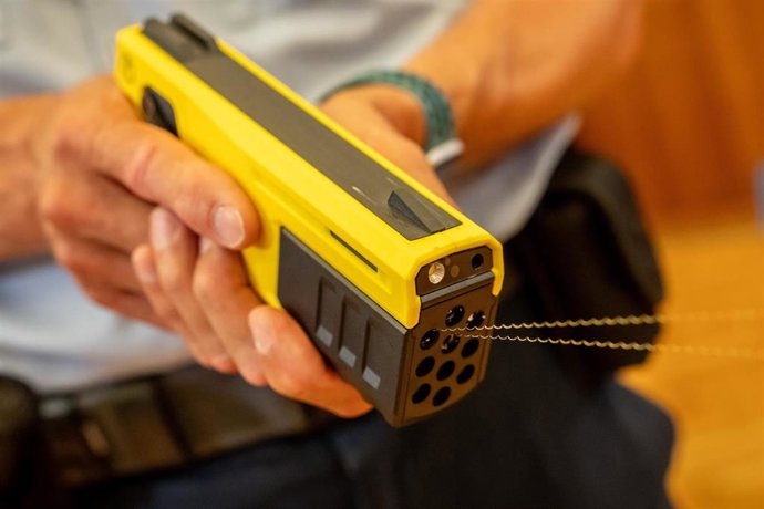 Archivo - FILED - 26 June 2025, Berlin: A German police officer demonstrates a Taser 10. The gun shoots darts at wires, whose electrical impulses can be used to "immobilize" attackers. German police officers are set to be allowed to carry and use Tasers n