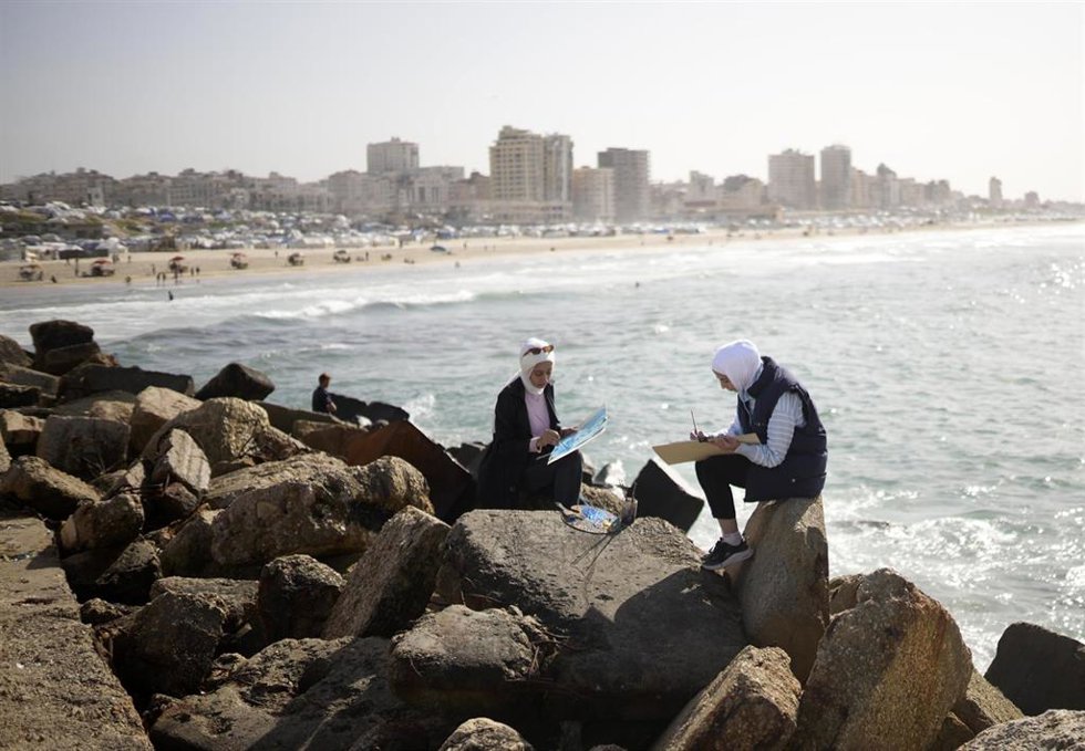 Dos mujeres gazatíes pintan en la costa de la Franja de Gaza