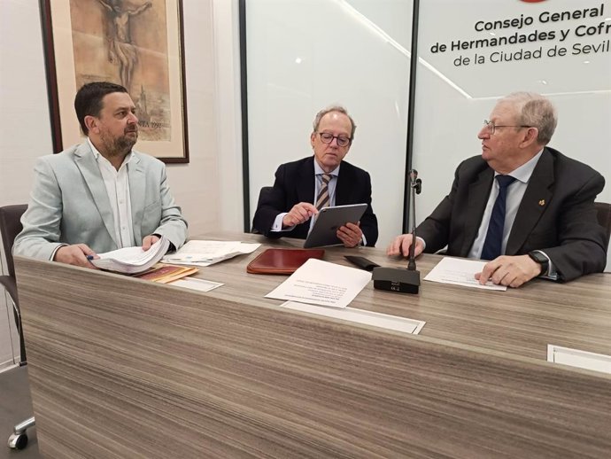 El notario Ignacio Guajardo-Fajardo Colunga (c) extrae el número del sorteo para la adjudicación de sillas de la carrera oficial, en presencia del presidente del Consejo de Hermandades, Francisco Vélez (d), en la sede del órgano cofradiero.