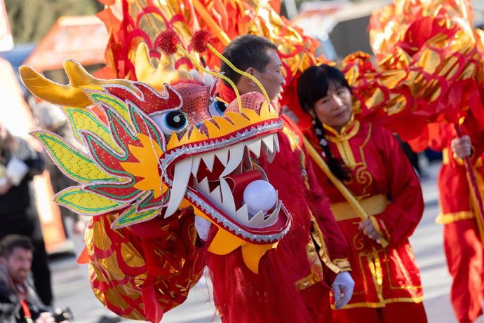 Archivo - Varias personas llevan un dragón en el mercadillo de artesanía china.