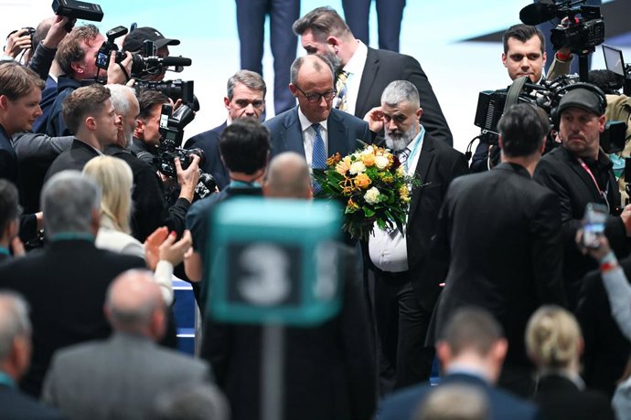 20 February 2026, Baden-Wuerttemberg, Stuttgart: German Chancellor Friedrich Merz (C) walks past journalists with a bouquet of flowers after his re-election as chairman at the Christian Democratic Union of Germany (CDU) federal party conference. Photo: Ka