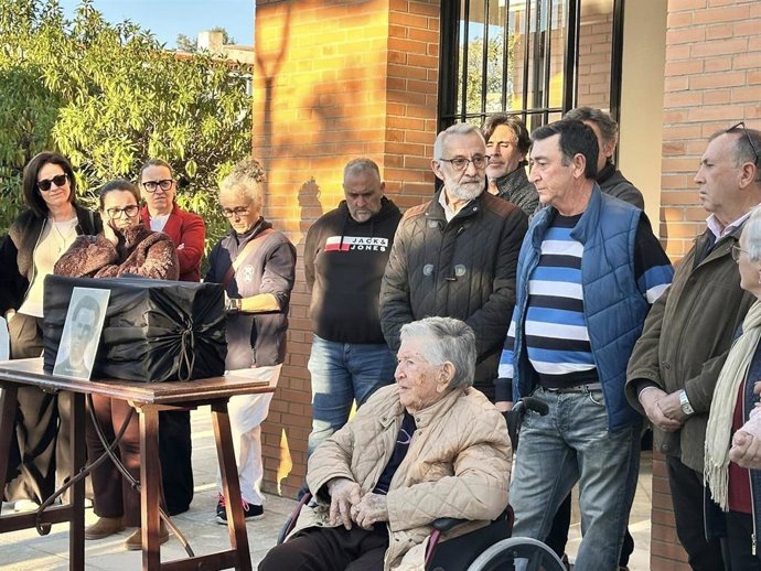 La hija del hombre asesindo durante la guerra civil (en silla de ruedas) junto a una foto de su padre, poco antes de enterrar sus restos en el cementerio de Bonares (Huelva).