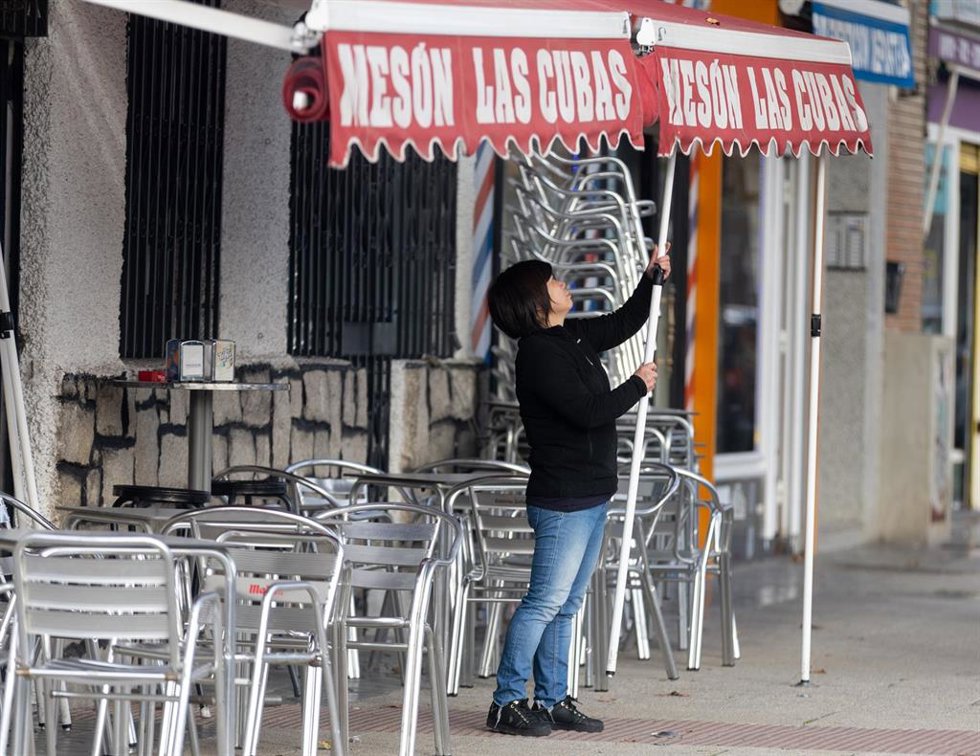 Archivo - Una camarera levanta el toldo de un bar