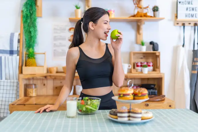 Joven en ropa deportiva comiendo sano en lugar de elegir comida basura.