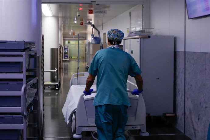 Archivo - Un celador transporta una camilla vacía en un pasillo que comunica los quirófanos de un hospital