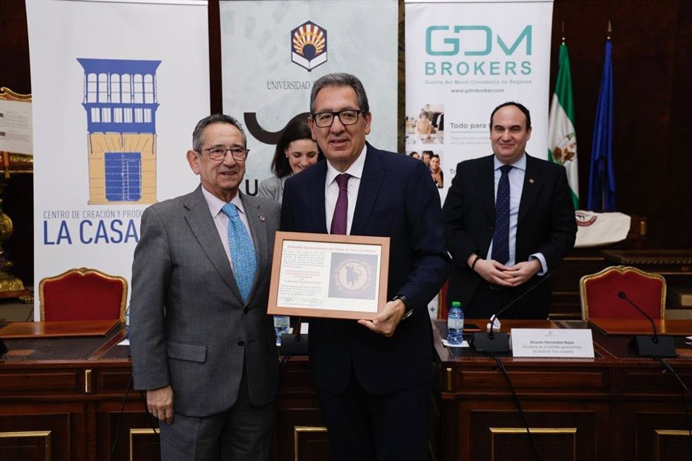 Antonio Pulido (centro) muestra su nombramiento como embajador de la Cofradía Gastronómica del Rabo de Toro Cordobés, tras entregárselo Ricardo Rojas (izda.).