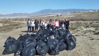 Voluntarios junto a las bolsas con residuos recogidos en las dunas del Peñón del Moro, en El Ejido (Almería).