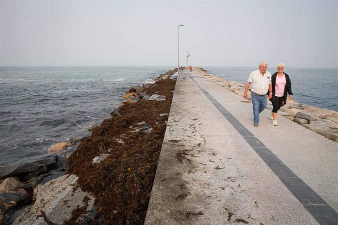 Archivo - Varias personas pasean durante la pleamar en el espigón de Foz, junto a la playa de A Rapadoira, a 19 de septiembre de 2024, en Lugo, Galicia (España). 