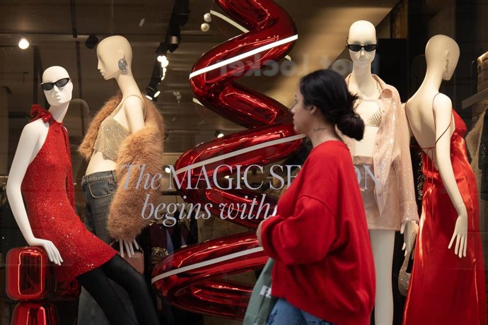 Archivo - Una mujer pasa por un escaparate durante la campaña de Navidad