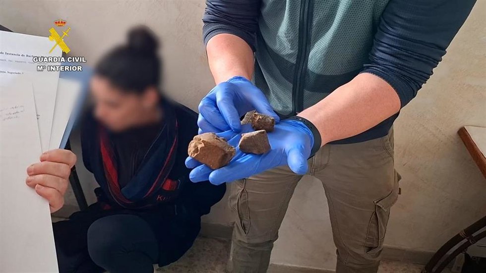 Un agente muestra un trozo de hachís incautado en un punto de venta de droga desarticulado en Barbate (Cádiz)