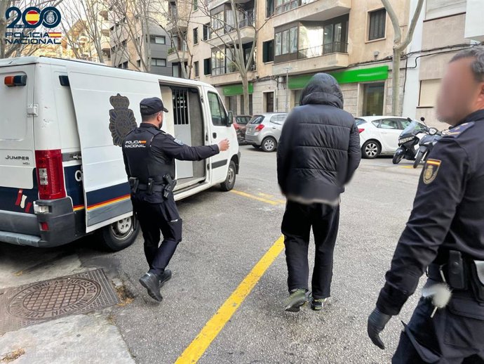 Uno de los arrestados, de espalda y escoltados por dos agentes de la Policía Nacional.