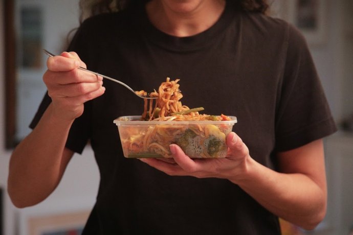 Chica comiendo un plato preparado de espagueti.