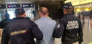 Agentes de la agencia de Migración de Colombia y de la Interpol retienen al ciudadano ruso Denis Alimov, buscado por Estados Unidos por supuestas actividades terroristas, tras su detención en el Aeropuerto de El Dorado, en la capital colombiana, Bogotá