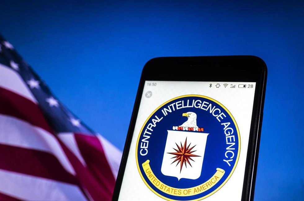 Archivo - Logo de la CIA en un teléfono móvil, con una bandera de Estados Unidos de fondo (archivo)