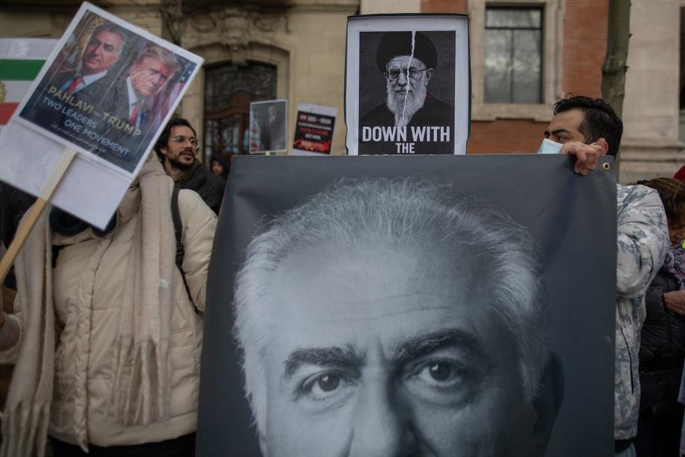 Un retrato rasgado del ayatolá Jomeini sobre un retrato gigante del rey de Irán, Reza Pahlavi, durante una manifestación de residentes iraníes en Madrid frente a la embajada de Estados Unidos