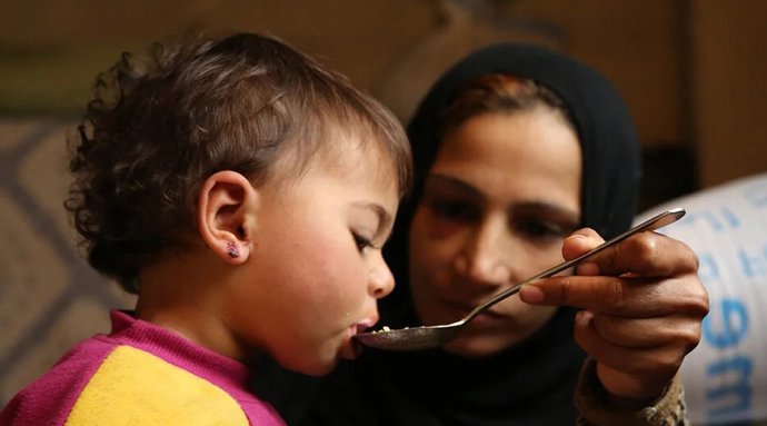 Una voluntaria alimentando a un niño.
