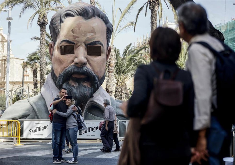 Archivo - Unos turistas se hacen una foto frente a una falla con el rosto de Sorolla diseñada y pintada por el artista Escif en la plaza de la Reina, a 13 de marzo de 2023