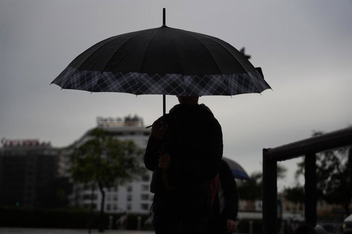 Archivo - Arxiu - Vianants es protegeixen de la pluja baix els seus paraigües en imatge d'arxiu
