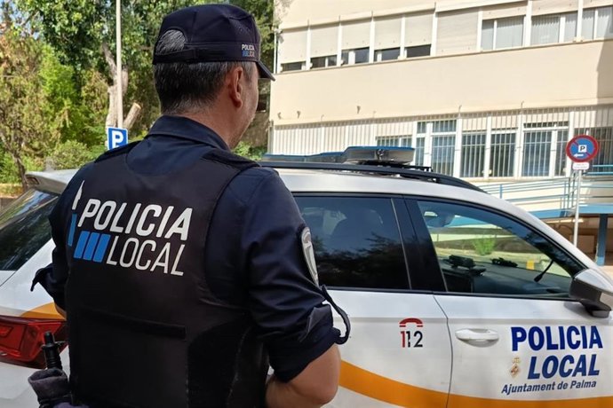 Agente de la Policía Local de Palma frente a un coche patrulla.