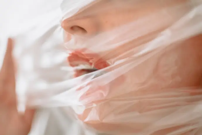 Primer plano de mujer cubriendo la boca con plástico