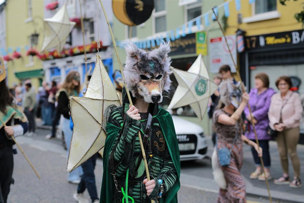 Persona con máscara de lobo y capa verde en el festival