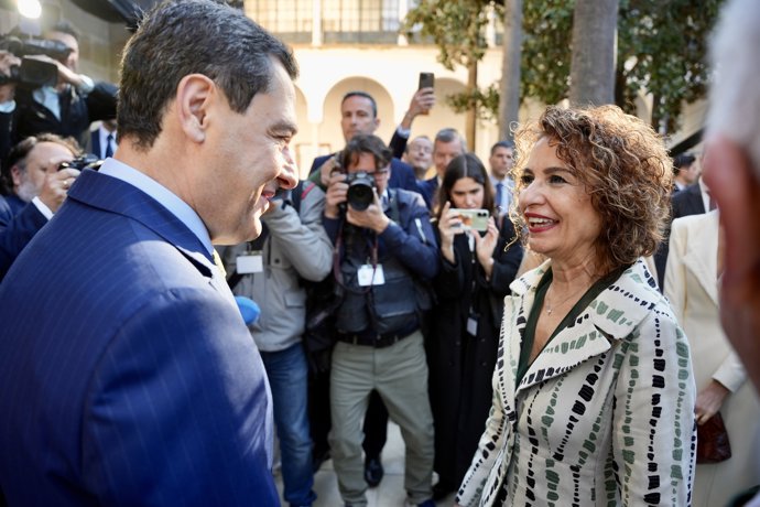 La vicepresidenta primera y ministra de Hacienda y candidata a la Junta de Andalucía del PSOE-A, María Jesús Montero saluda al presidente de la Junta de Andalucía, Juanma Moreno (d) a su llegada al acto del Día de Andalucía.